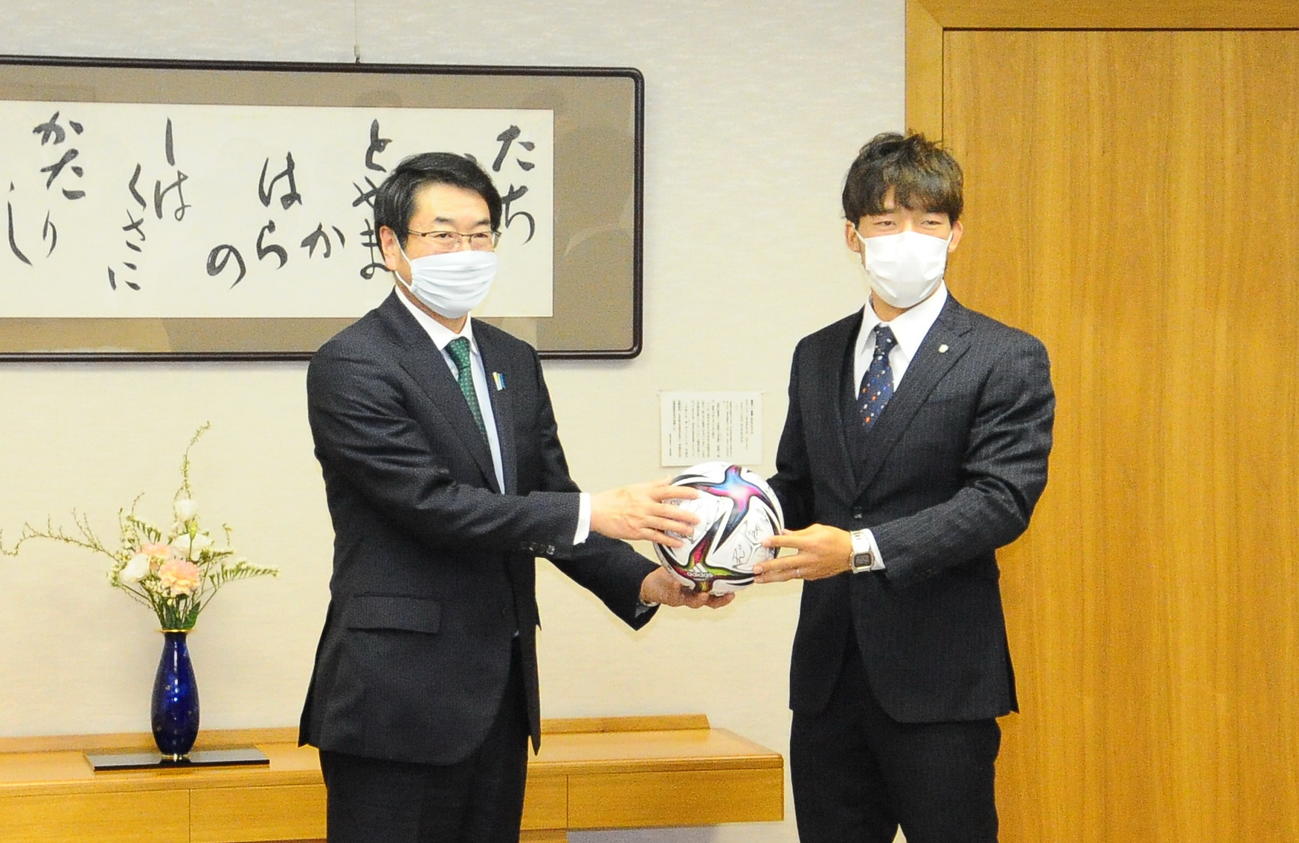 選手のサイン入りボールを新潟市の中原市長に渡す新潟鈴木（右）