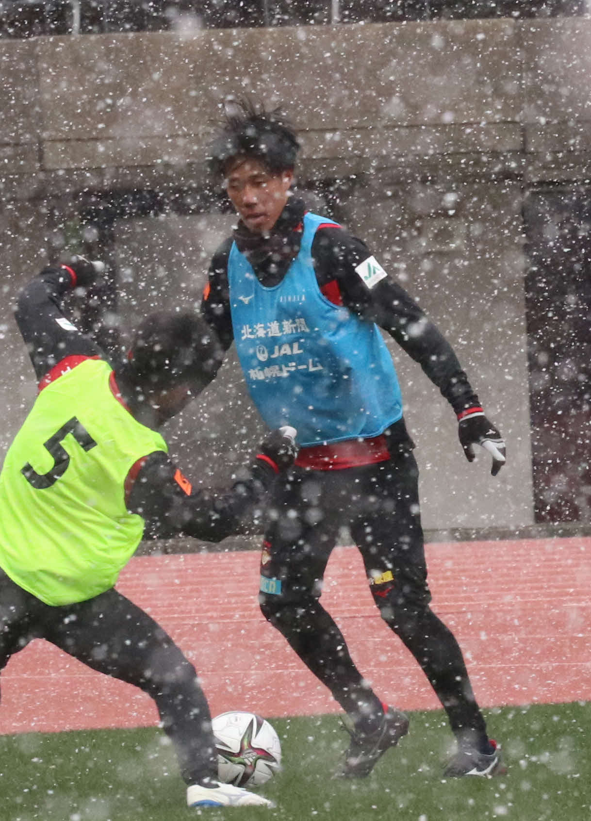 雪が舞う中、ボールをキープする札幌DF田中（撮影・浅水友輝）