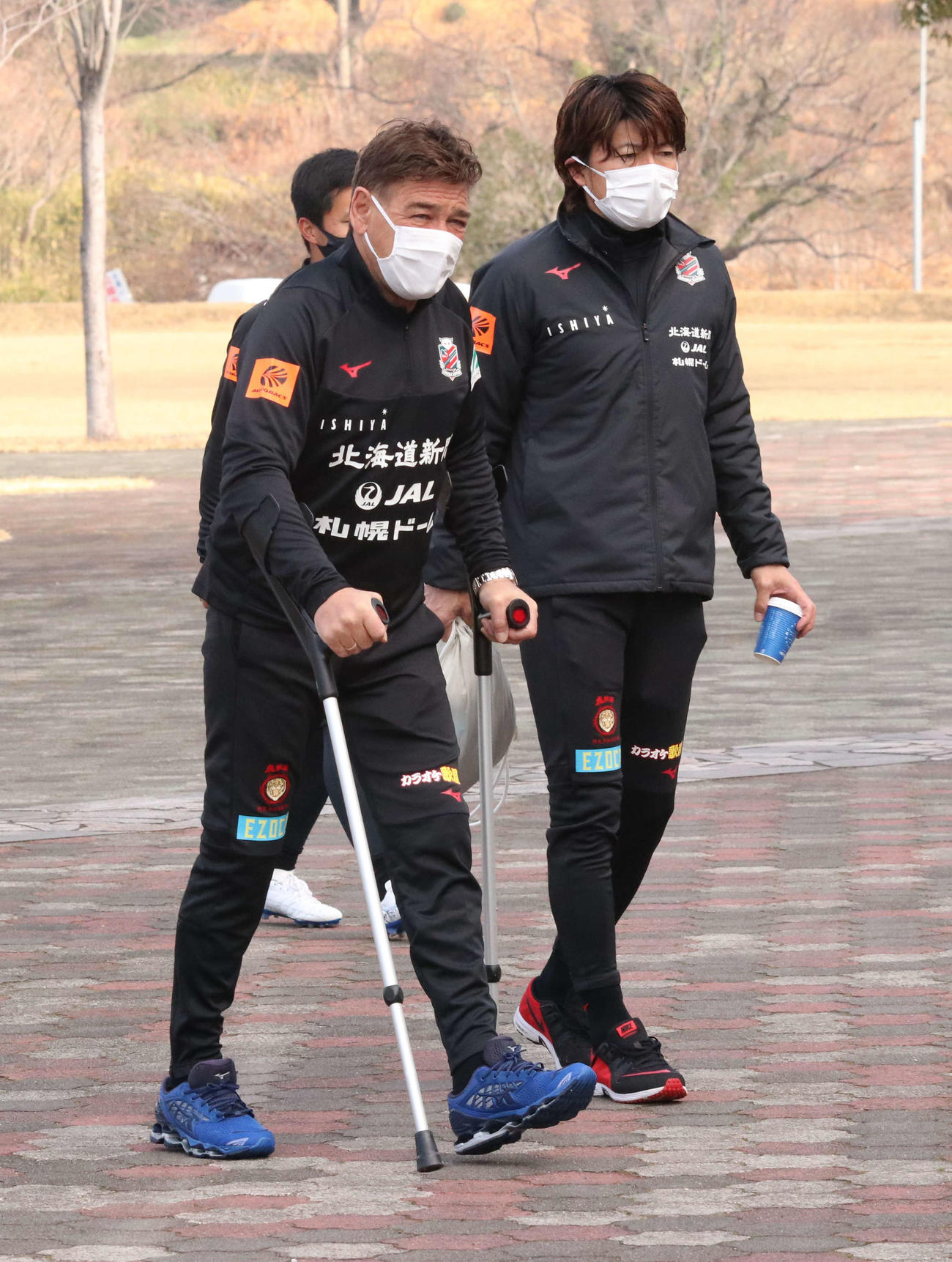 松葉づえ姿ながら元気な足取りでチーム活動に合流した札幌ペトロビッチ監督（左）（撮影・浅水友輝）