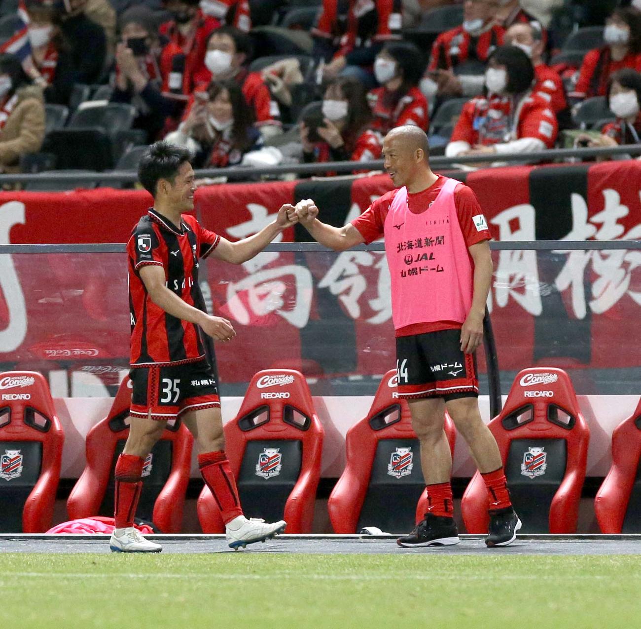 札幌対横浜FC　ベンチ前でグータッチを交わす札幌FW小柏（左）とMF小野（撮影・佐藤翔太）
