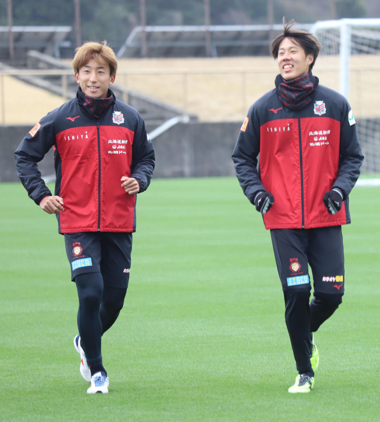 笑顔でランニングする札幌DF田中（右）。左はMF金子（c）2021 CONSADOLE