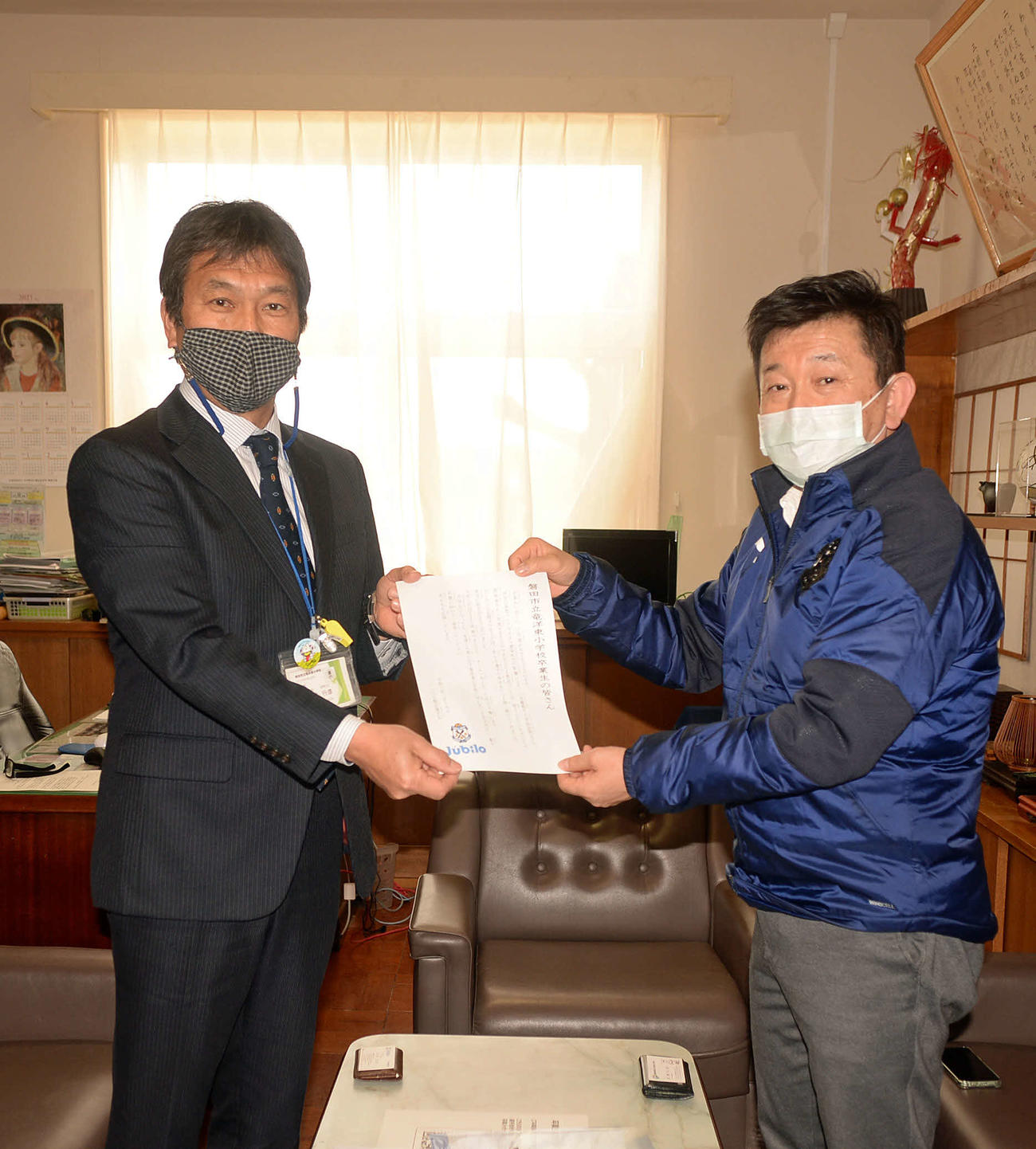 選手会からの祝電を手に記念撮影する、磐田市立竜洋東小の黒野校長（左）と磐田ホームタウン部の加藤部長