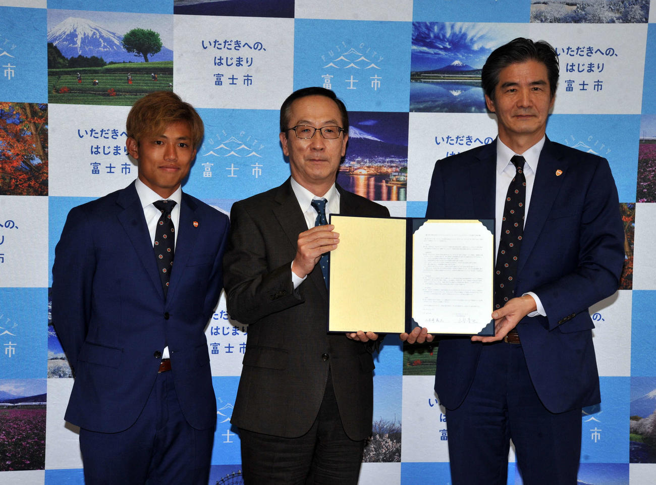 記念写真に納まる左から清水MF石毛、富士市の小長井市長、清水の山室社長