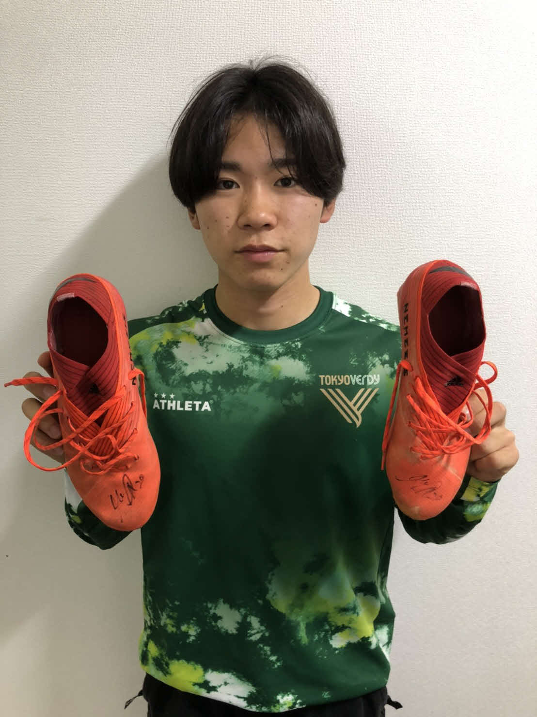 オークションに出品するサイン入りスパイクを手にする東京Vの17歳MF阿野真拓（（C）TOKYO VERDY）