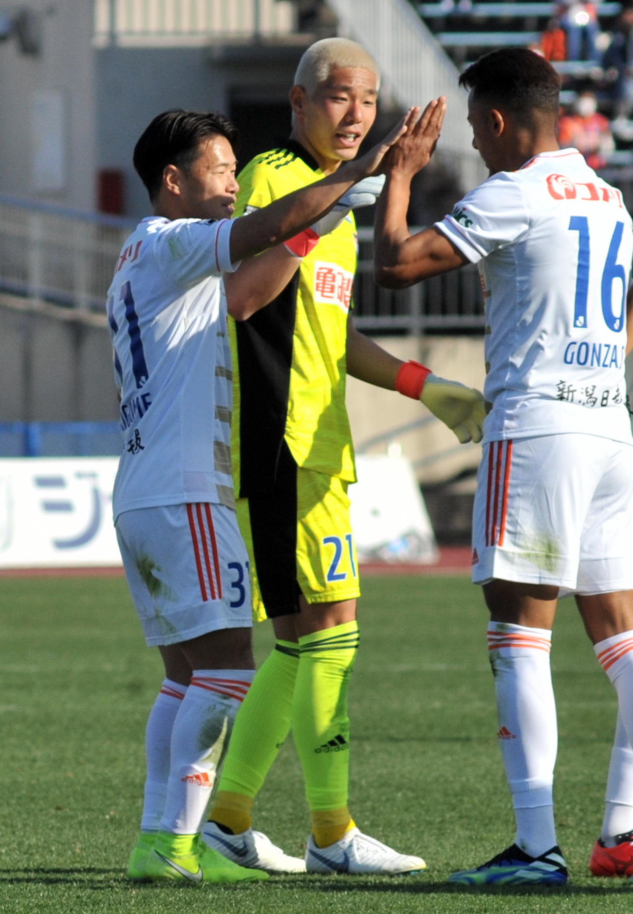 敵地で完封勝ちした新潟はDF堀米主将（左）とGK阿部らがハイタッチをかわす