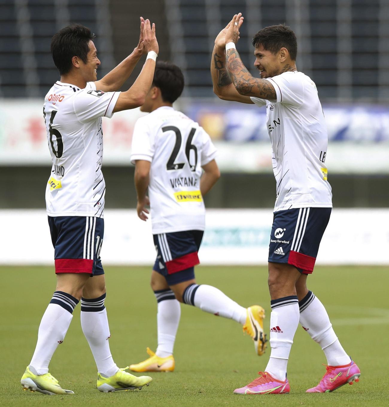 前半、先制ゴールを決め、高野（左）とタッチを交わす横浜レオ・セアラ（共同）