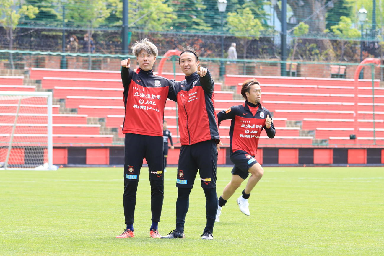 練習後、カメラに向かってポーズを決める札幌DF田中駿（左）とMF荒野（右）。後方はMF駒井（撮影・保坂果那）