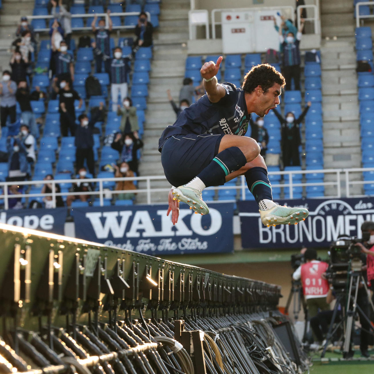福岡対湘南　後半20分、ゴールを決めた福岡ブルーノ・メンデスは看板を跳び越えてサポーターの元へ駆け寄る（撮影・屋方直哉）