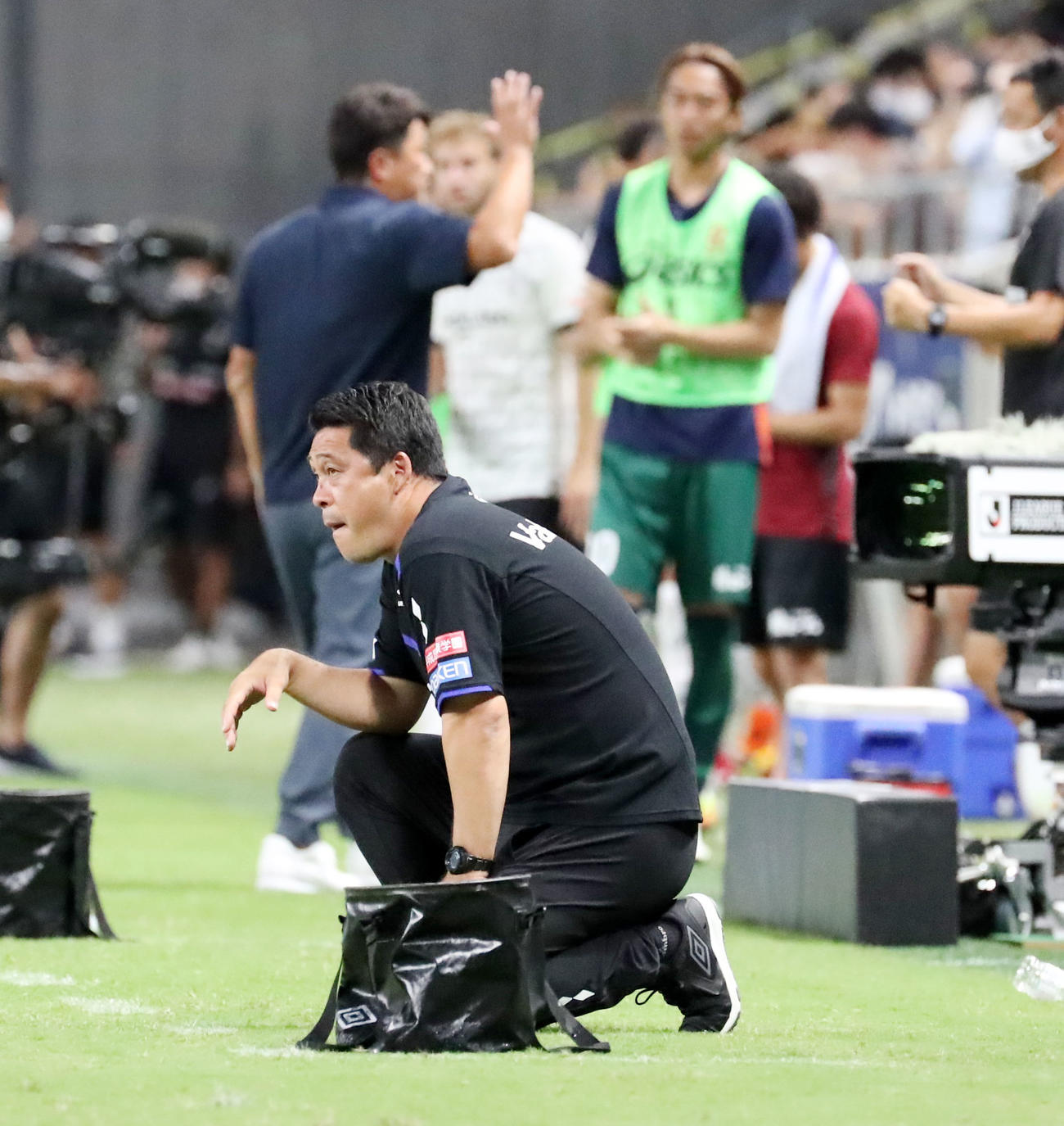 G大阪対神戸　後半ロスタイム、最後のプレーで得点できずひざまずくG大阪松波監督。後方は勝利して関係者とタッチする神戸の三浦監督（撮影・加藤哉）
