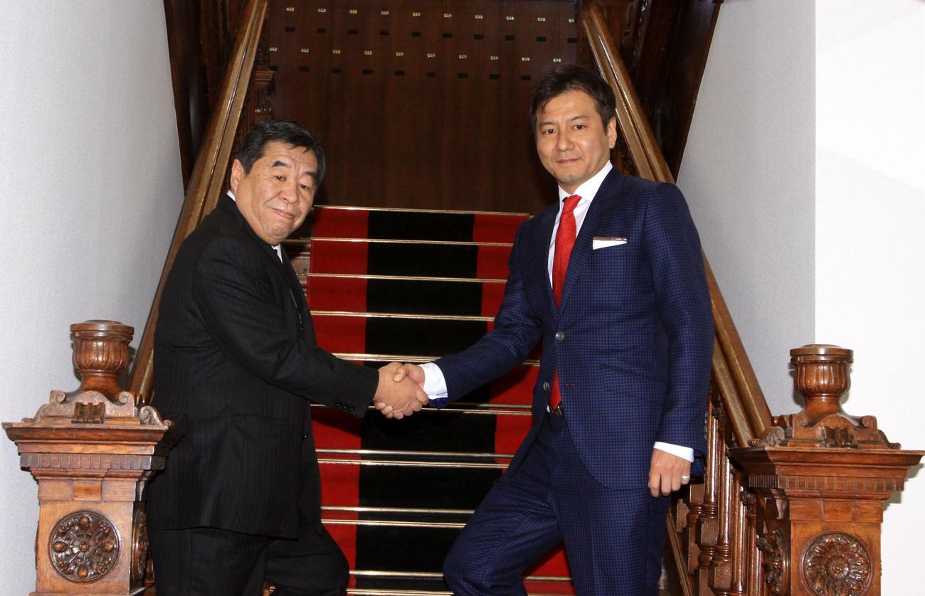 新事務所の階段で石屋製菓の石水勲会長（左）と握手する野々村芳和社長（2014年1月29日撮影）
