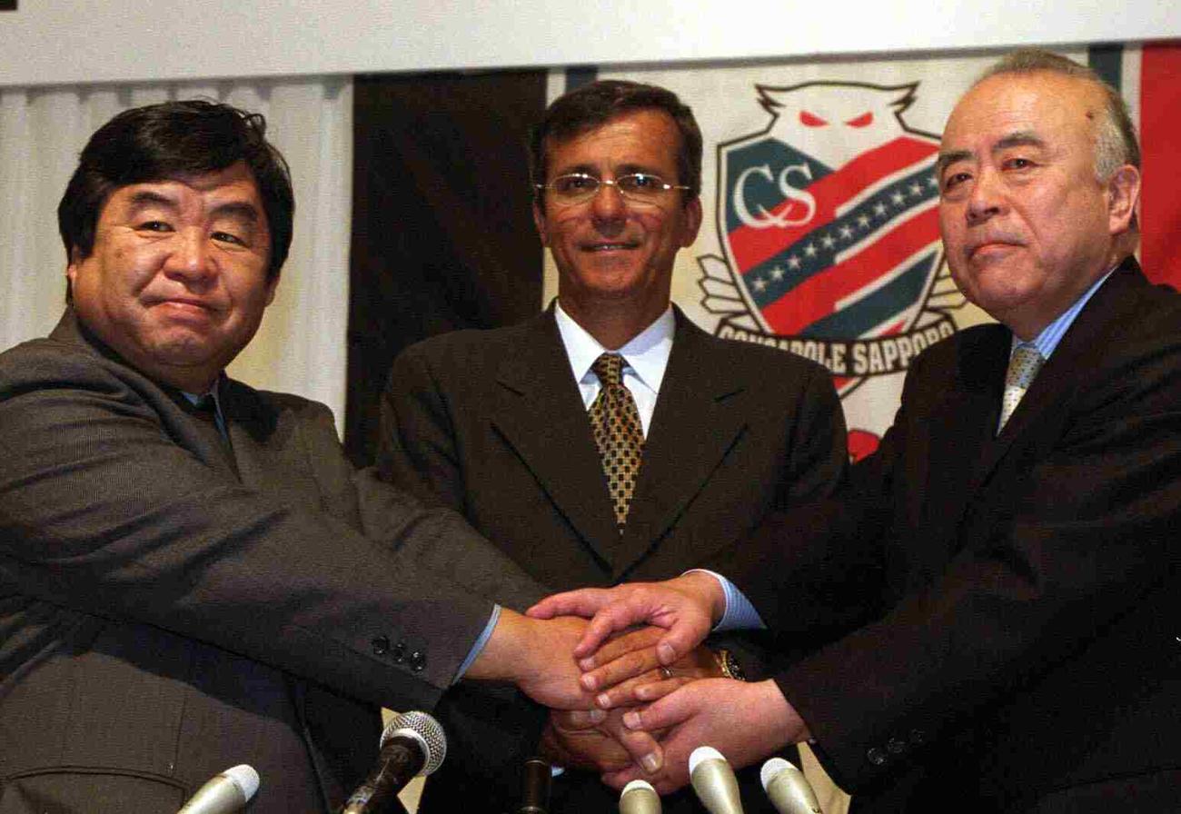 02年、ジョアン・カルロス新監督（中央）の就任会見で握手する石水氏（左）