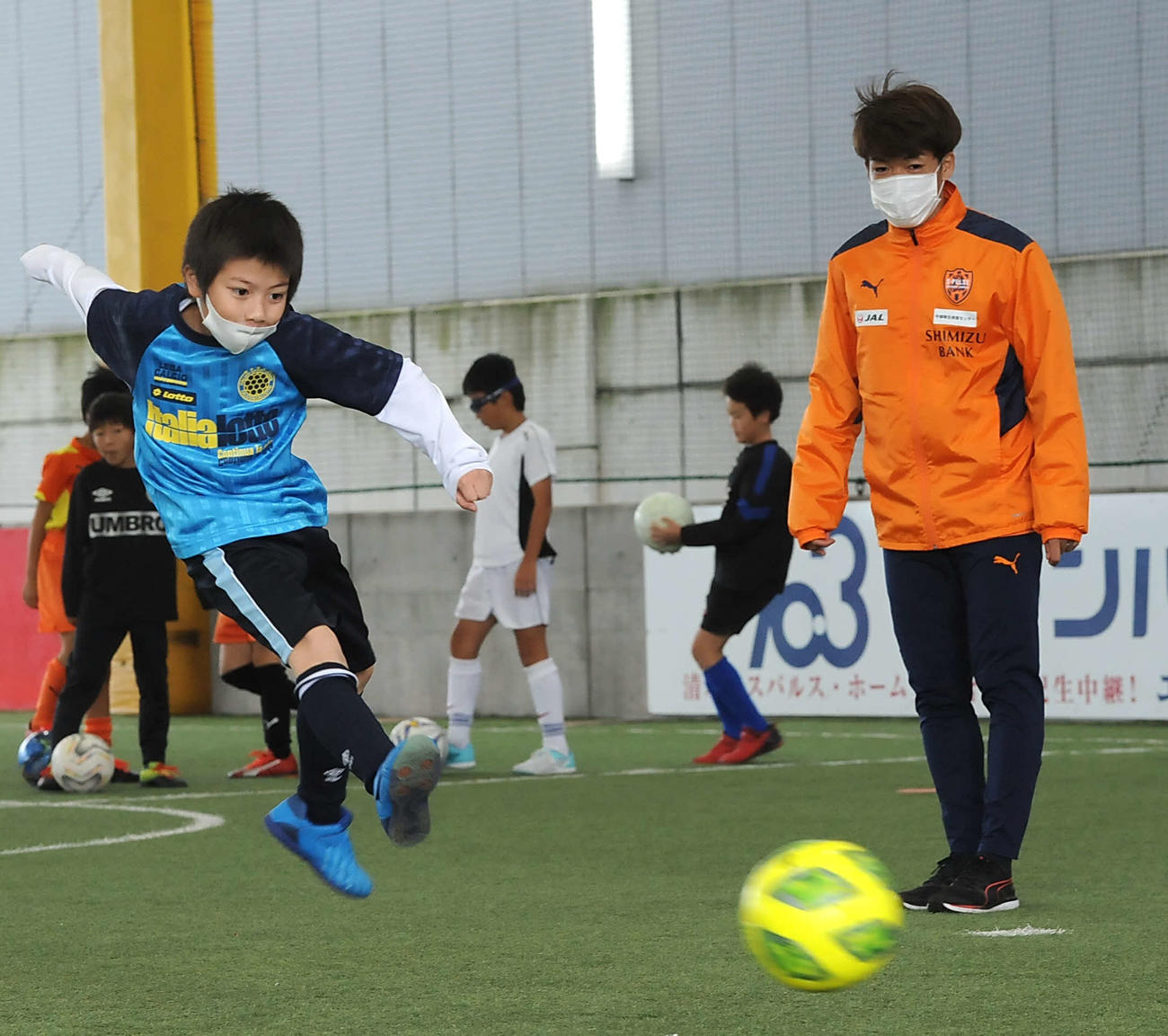 J1清水の西沢（右）は、シュートをする男子児童を見守る