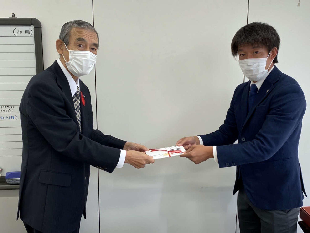 沼津市社会福祉協議会の工藤会長（左）に寄付金を手渡す沼津MF菅井（アスルクラロ沼津提供）