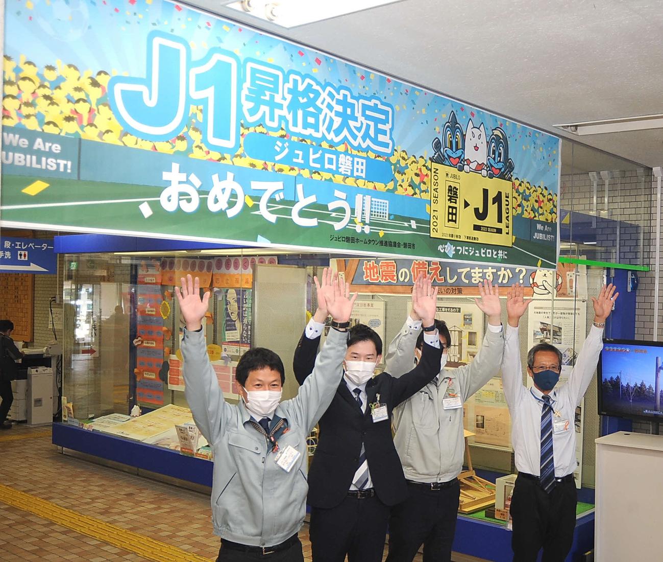 庁舎内に祝福の横断幕を掲出して万歳する磐田市役所の職員ら
