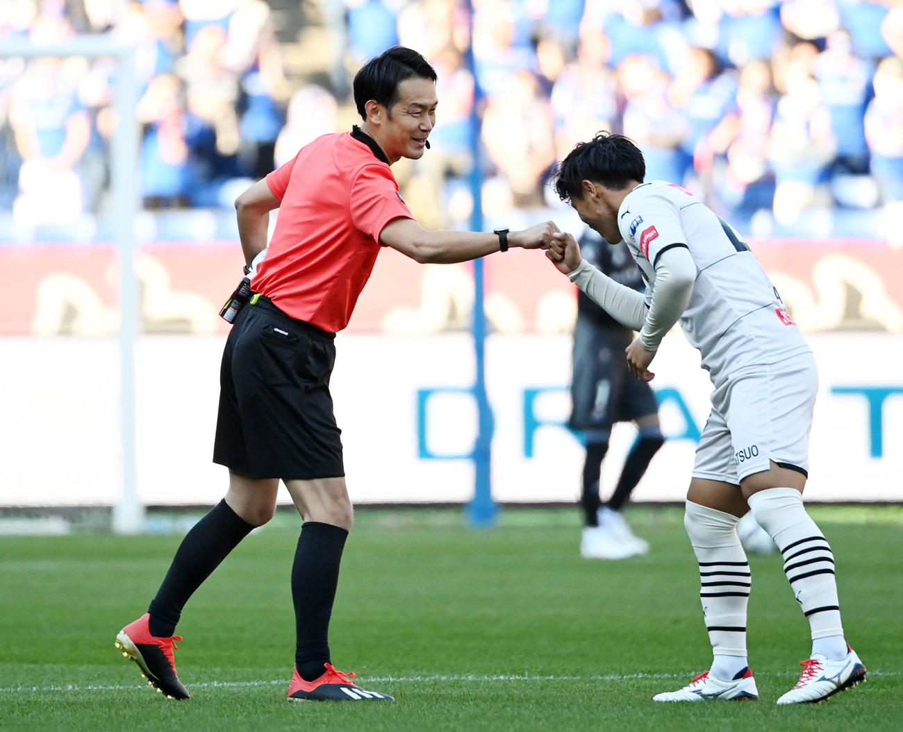 横浜対川崎F　試合前、川崎F旗手（右）とタッチを交わす家本審判員（撮影・横山健太）
