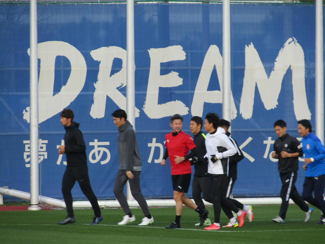 大阪府内で自主トレを始めたカズ（左から3人目）は後輩Jリーガーらと「DREAM」の横断幕の前でランニング