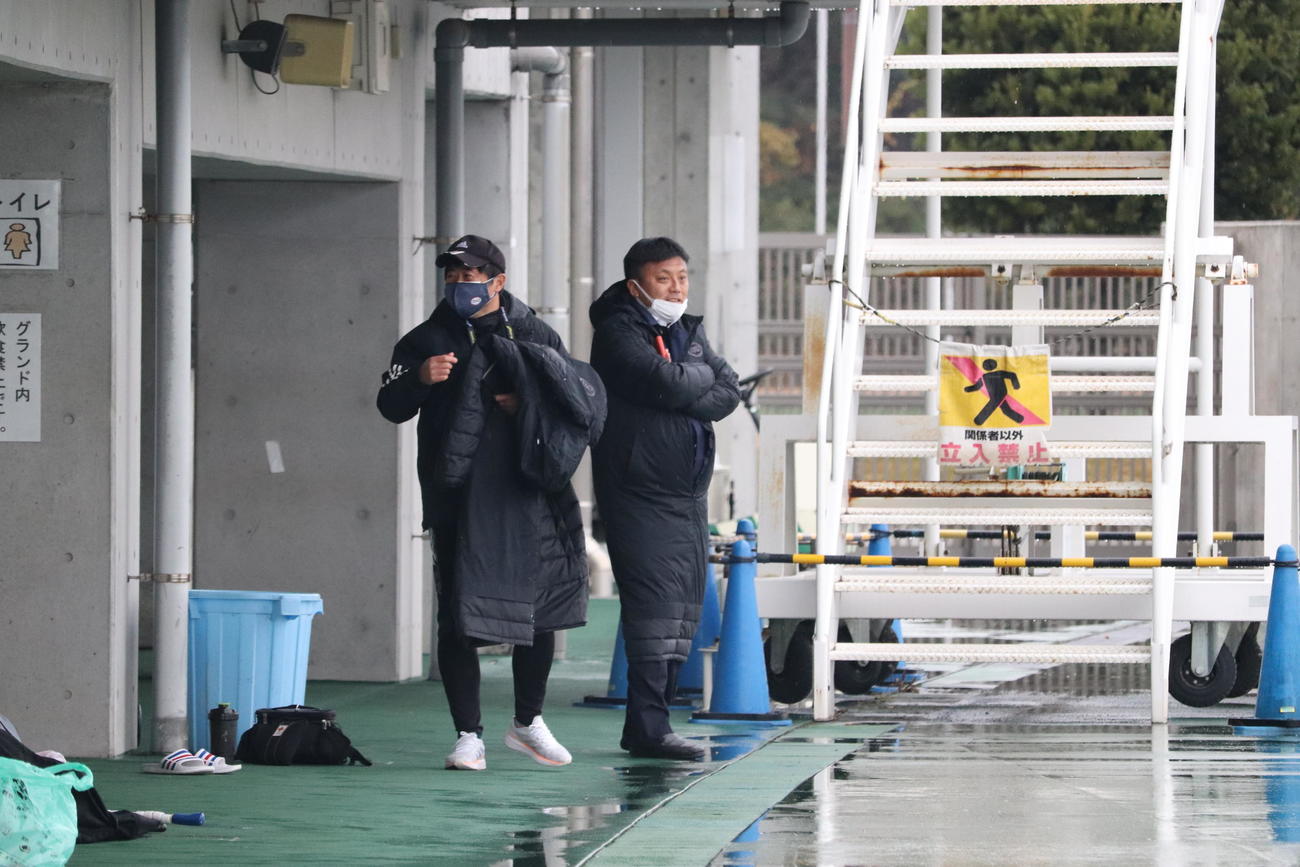 昨年コーチを務めた流通経大の選手をベンチ外から見守る京都の曹貴裁監督（右）