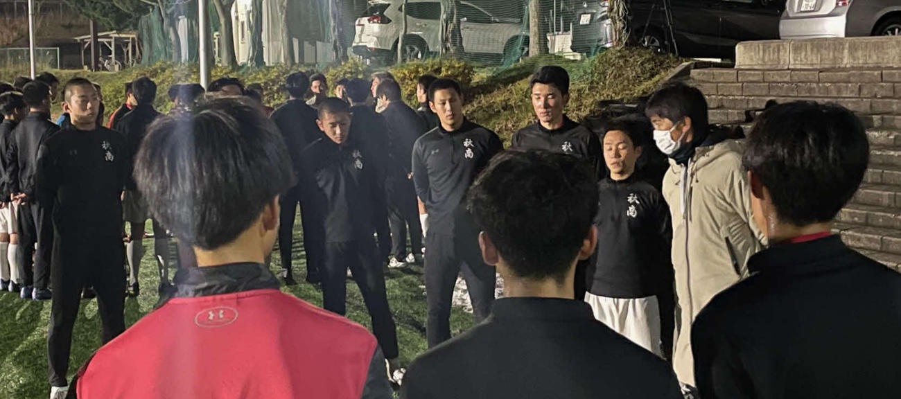 学校に隣接された人工芝のグラウンドで、練習後にメンバーに話をする秋田商・小林監督（右から2人目）