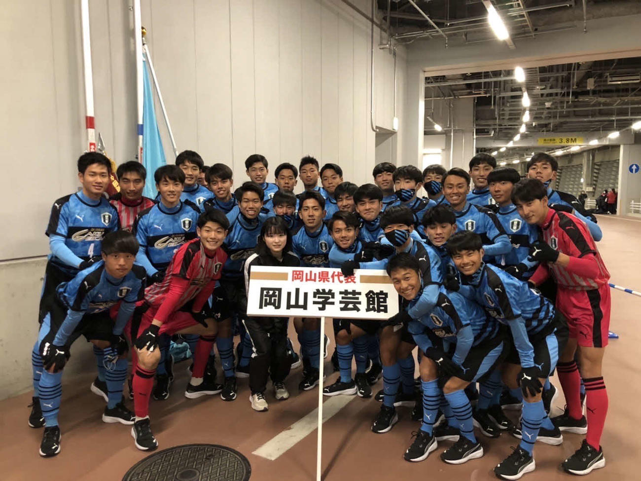 岡山学芸館のMF三並（2列目右から3番目）※プラカードの右上のマスクの選手