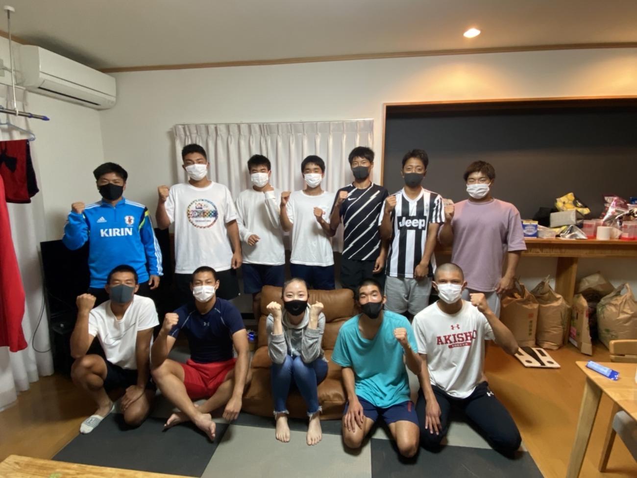 被っていたウィッグを外し、寮生に丸刈り姿を見せた後、記念撮影する秋田商サッカー部の寮母・赤坂郁子さん（1列目、中央）