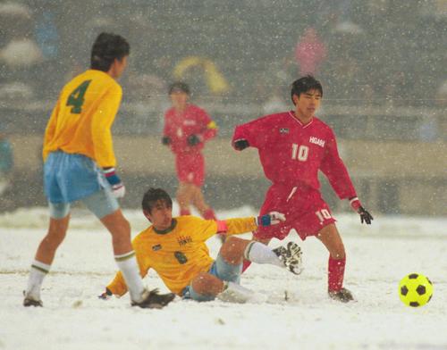 98年1月、降雪の決勝となった帝京戦で東福岡・本山（右）は相手DFを交わしドリブル突破する。中央は帝京・中田