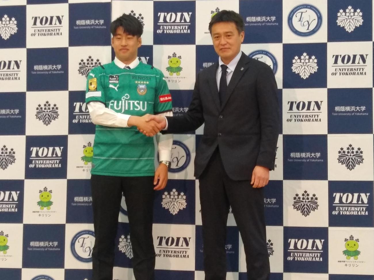 川崎Fの加入が内定した桐蔭横浜大のGK早坂勇希（左）は川崎Fの竹内弘明強化本部長と握手する