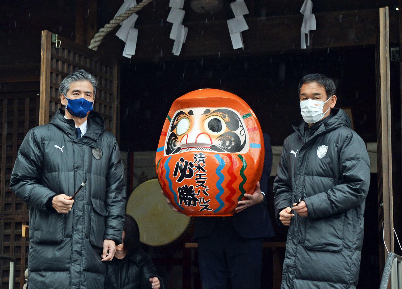 必勝だるまに墨入れした山室社長（左）と平岡監督
