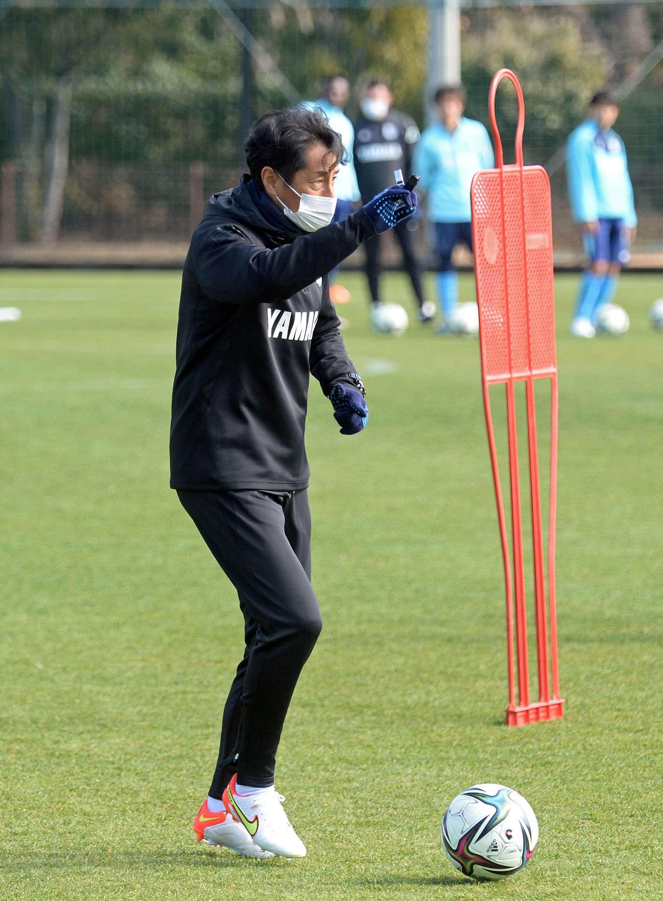 練習中にボールを使って手本を見せる磐田の伊藤監督＝15日