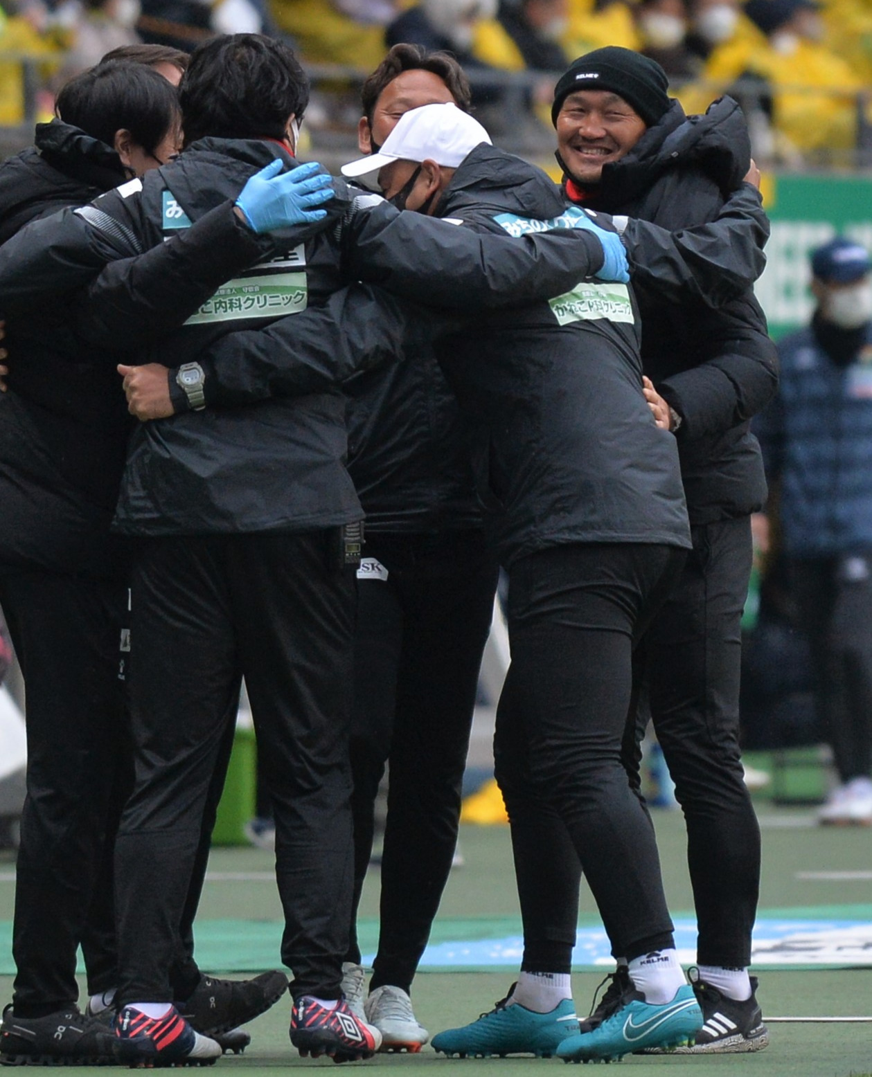 開幕戦に勝利し、笑顔で首脳陣と抱き合う秋田監督（右）