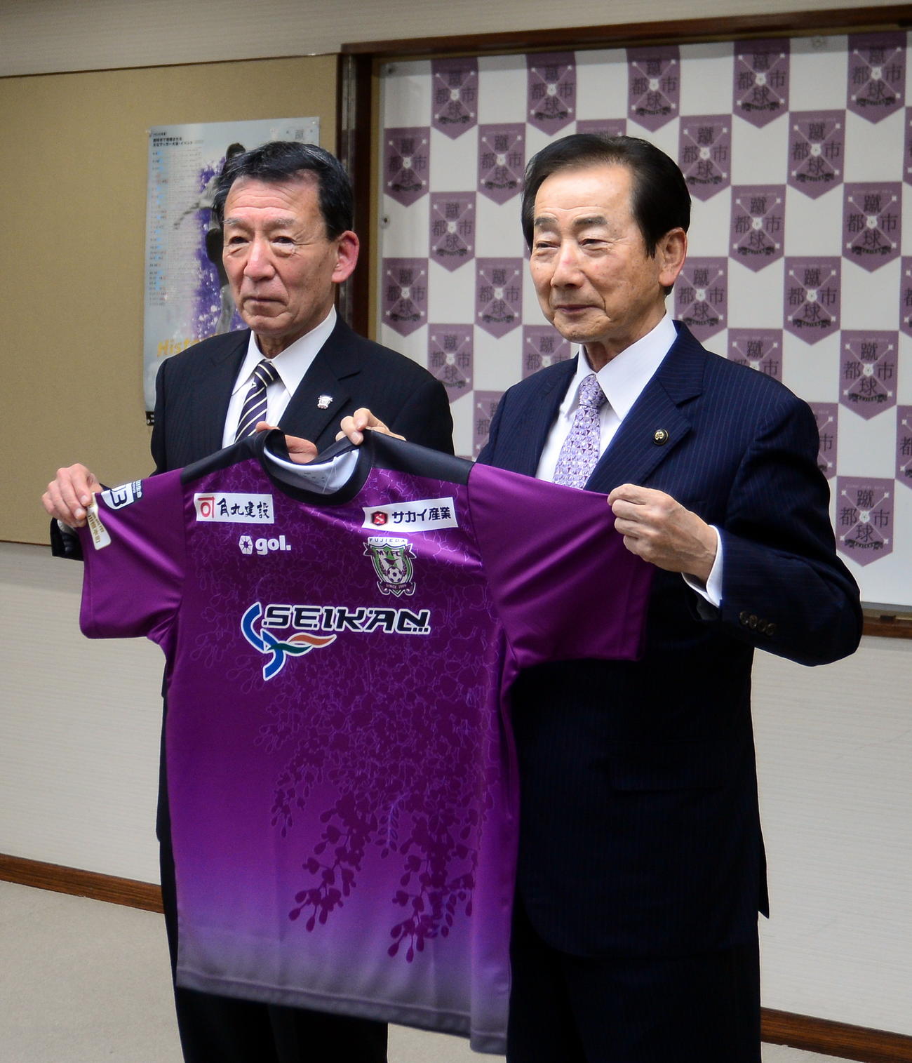 藤枝の鎌田会長（左）からユニホームを贈られた北村市長は、笑顔で記念撮影に納まる（撮影・前田和哉）