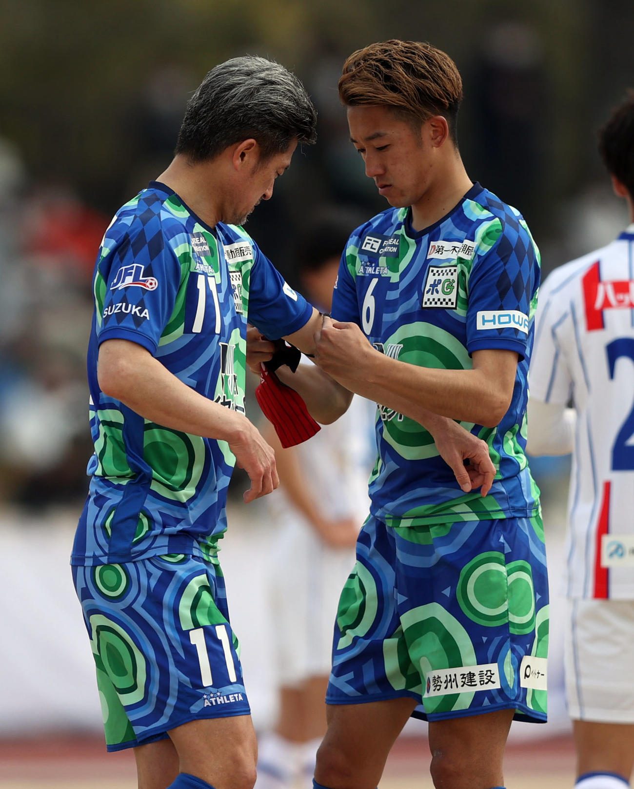 鈴鹿対青森　後半途中、キャプテンマークをつけてもらう鈴鹿カズ（左）（撮影・狩俣裕三）