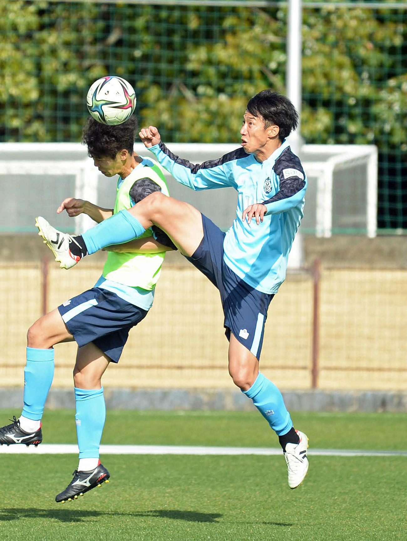 クロスに飛び込む磐田大津（右）