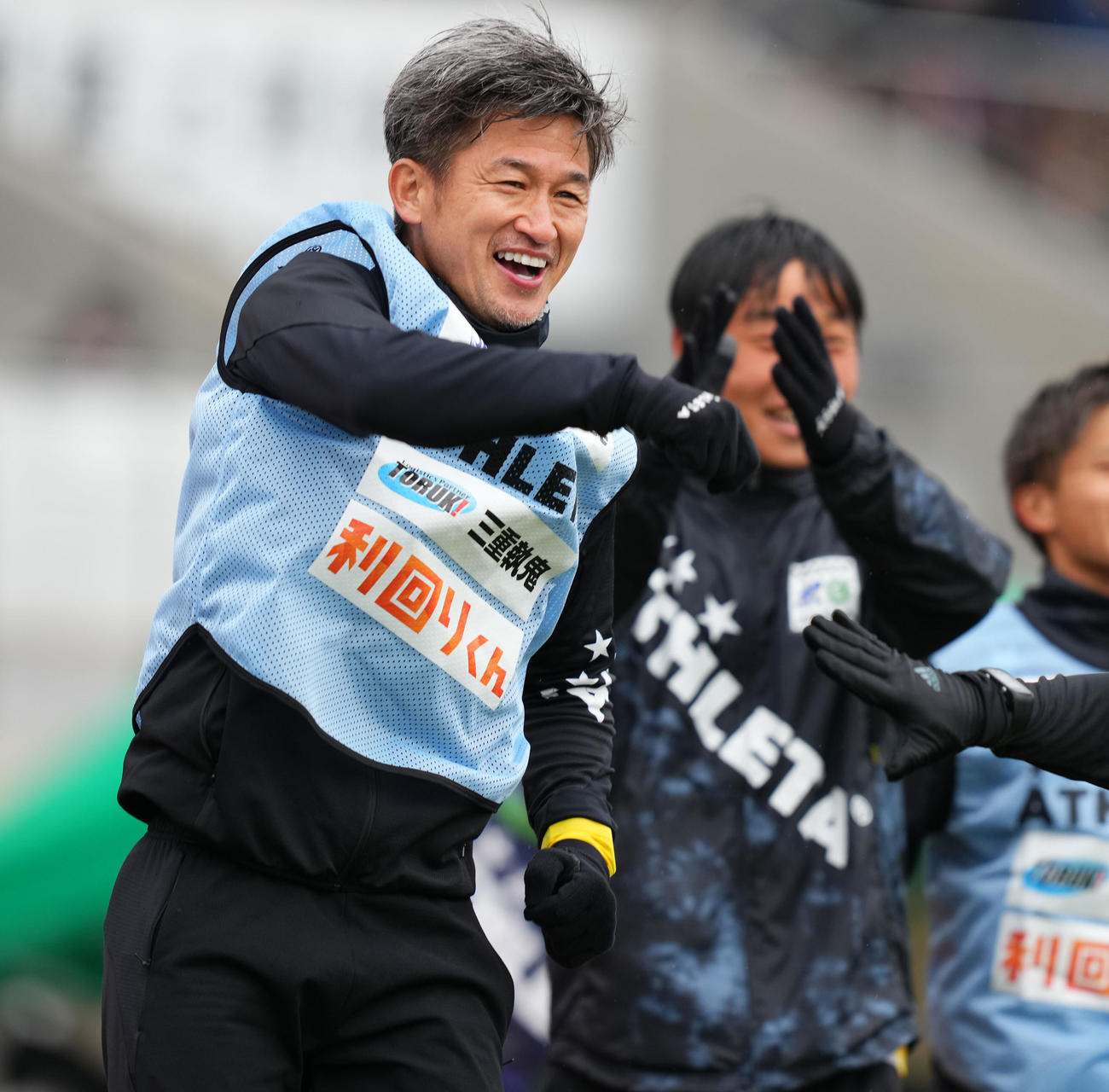 東京武蔵野対鈴鹿　後半、鈴鹿マークがゴールを決め笑顔を見せるカズ（左）（撮影・横山健太）