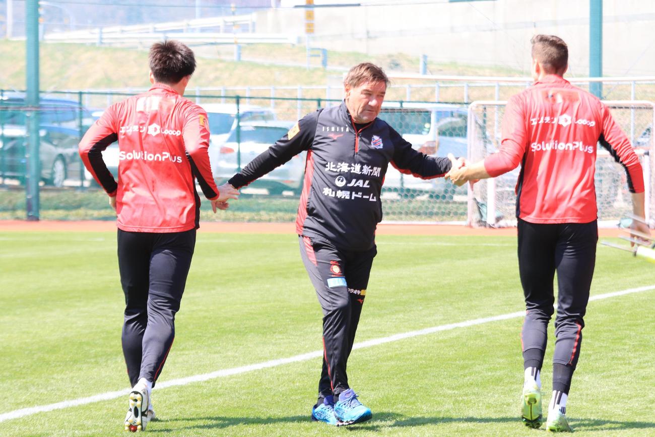 ランニングする深井（左）とトゥチッチ（右）とあいさつする札幌ペトロビッチ監督（撮影・保坂果那）