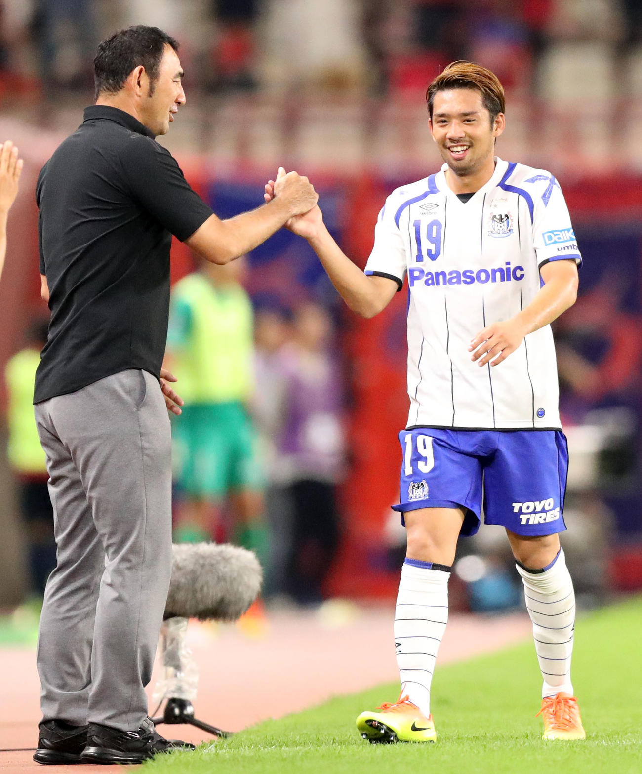 G大阪長谷川監督（左）と笑顔でタッチを交わすMF大森晃太郎（2016年7月2日撮影）