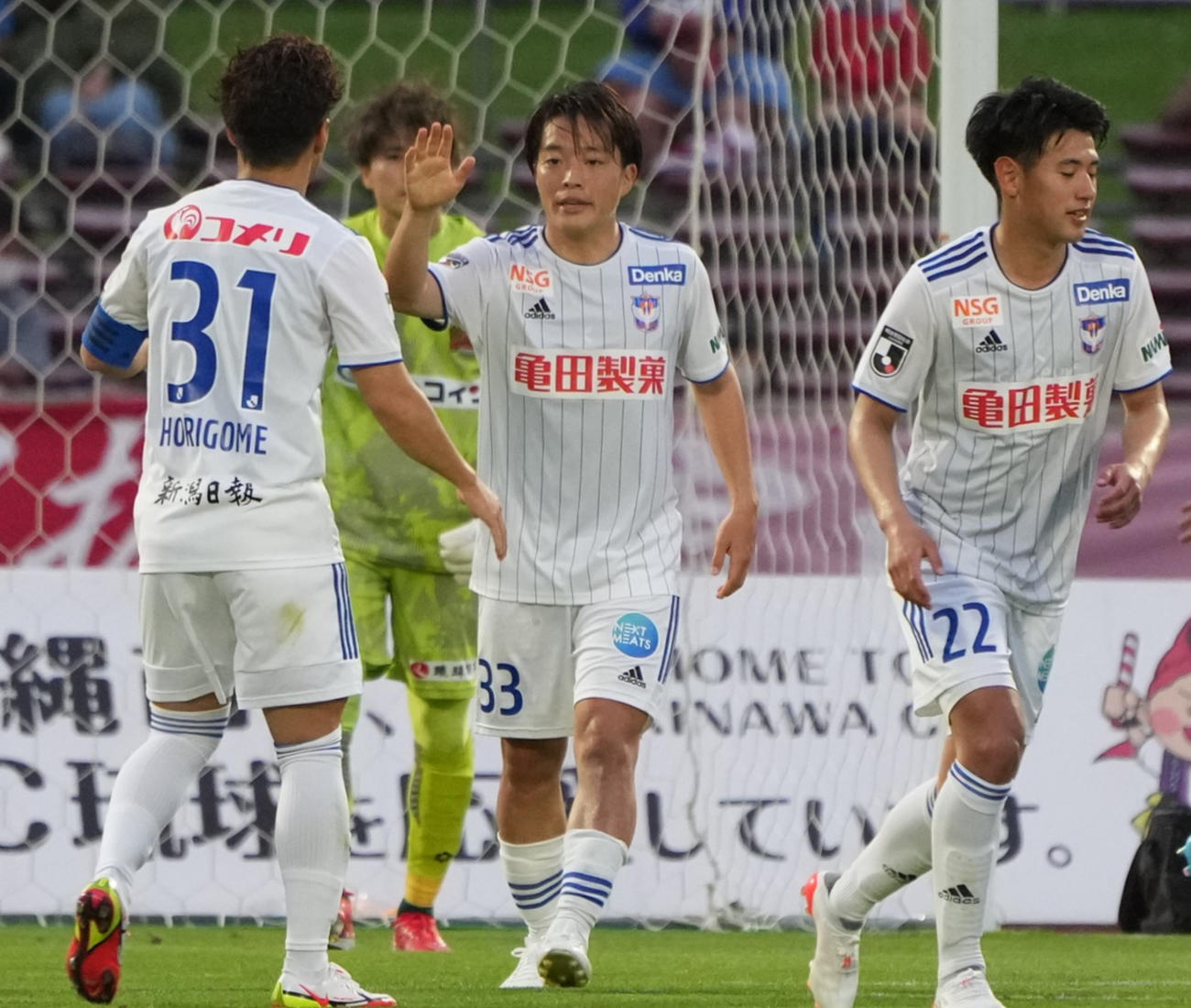 前半、新潟高木（中央）が同点のPKを決めチームケートと喜ぶ（沖縄タイムス提供）