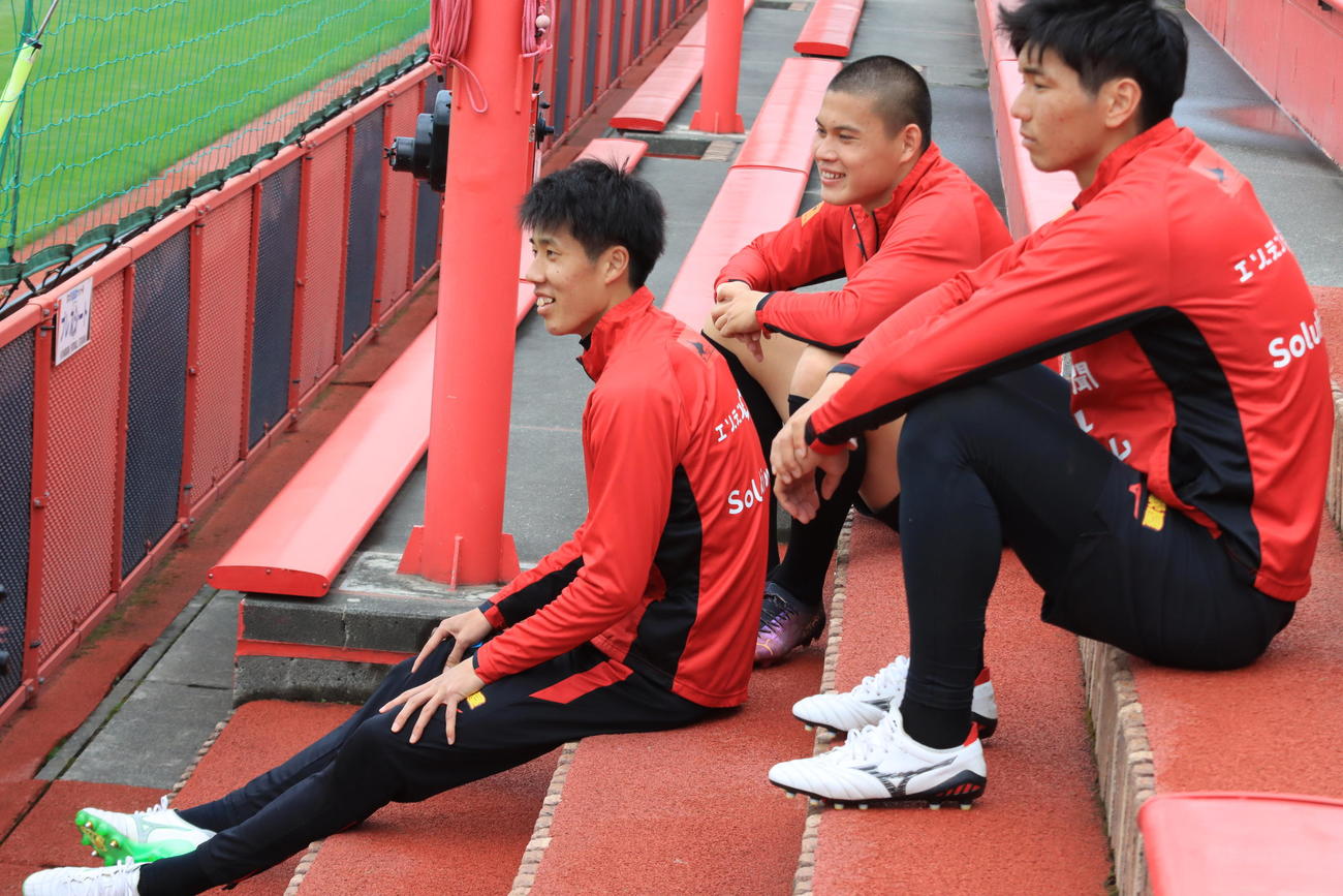 鹿島戦前日練習後、座って休む札幌田中駿（左）。中央は中島、右は中村（撮影・保坂果那）
