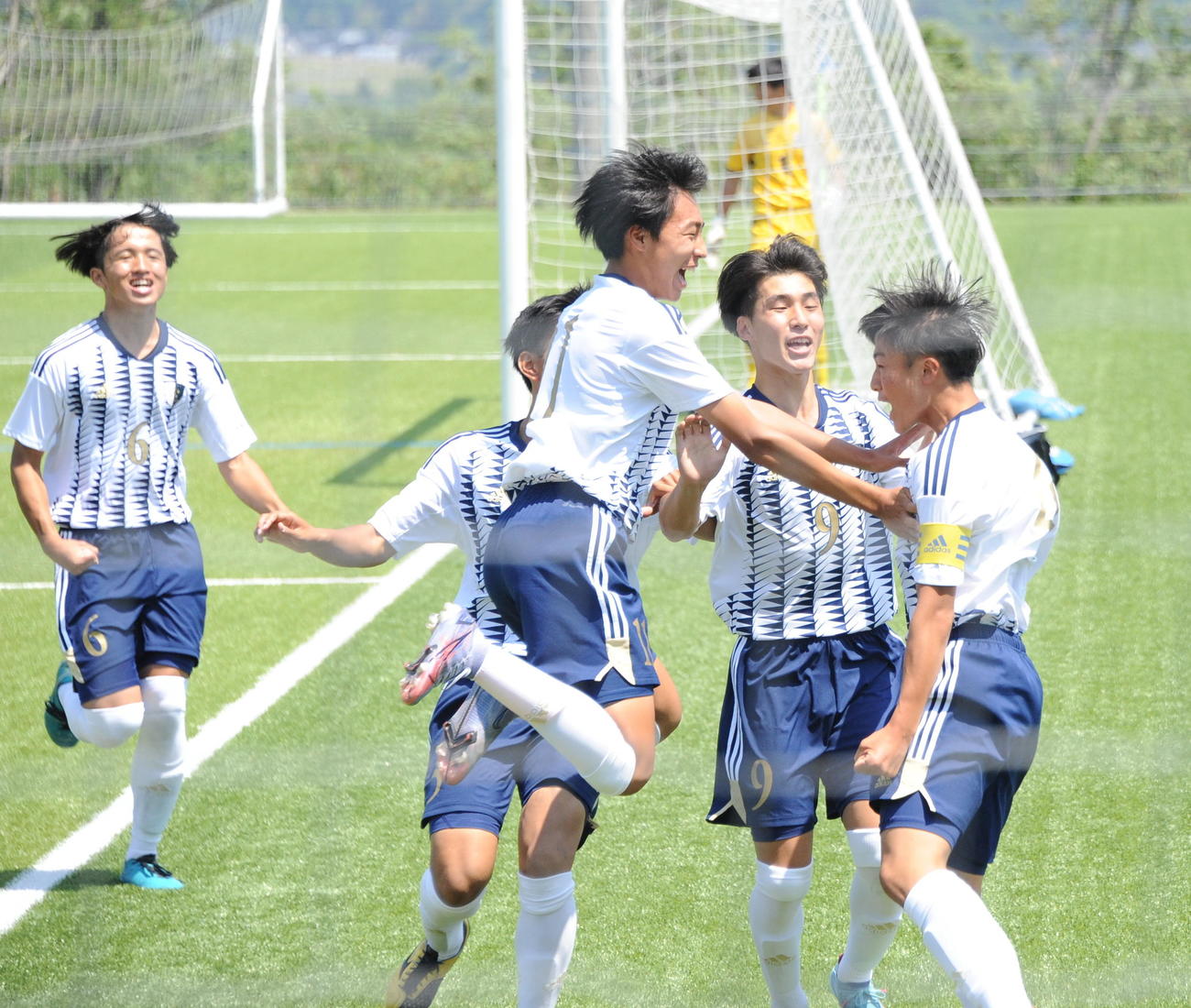前半4分に右FKから決勝点を決めた新潟明訓・加藤主将（右）にチームメートが飛びつく