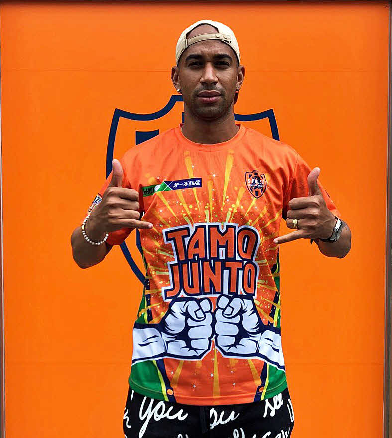 プレゼントされるTシャツを着てポーズを決める清水サンタナ