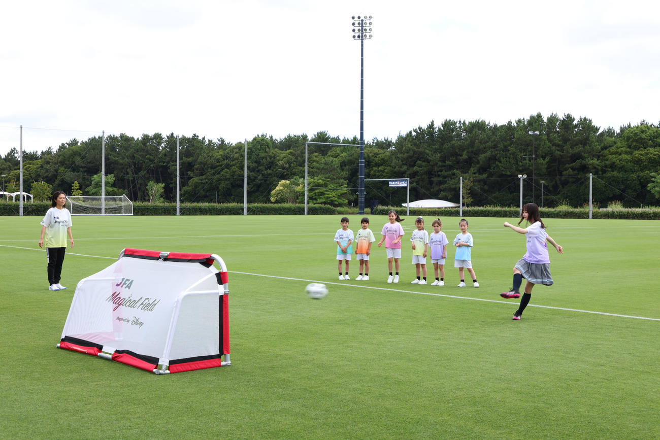 元サッカー女子日本代表の澤穂希さん（左奥）の前でシュートを放つ日向坂46影山優佳（C）Disney JFA Magical Field Inspired by Disney