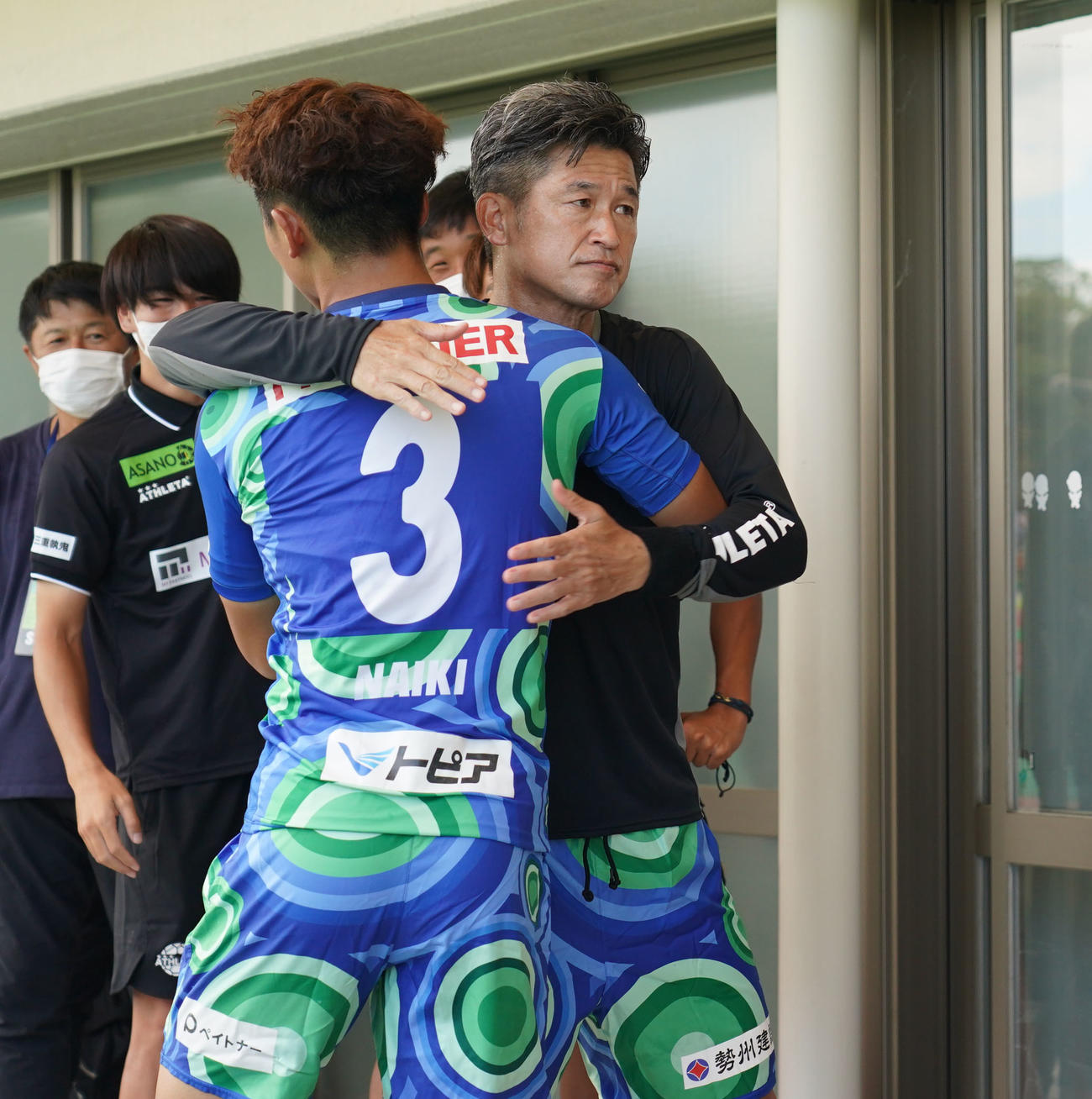 鈴鹿対三重　試合開始前、選手を送り出す三浦知（右）（撮影・森本幸一）