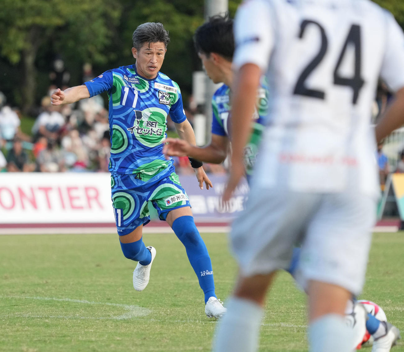 鈴鹿対三重　後半、ゴール前のボールに飛び込む鈴鹿・三浦知（左）（撮影・森本幸一）