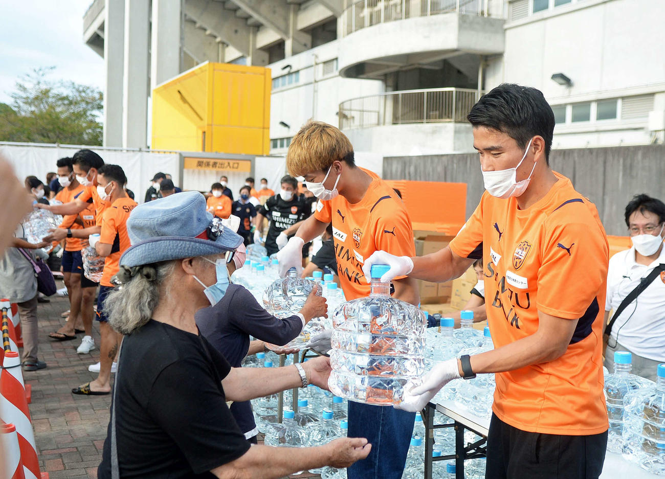 市民らに飲料水を配る清水鈴木義（右）や立田