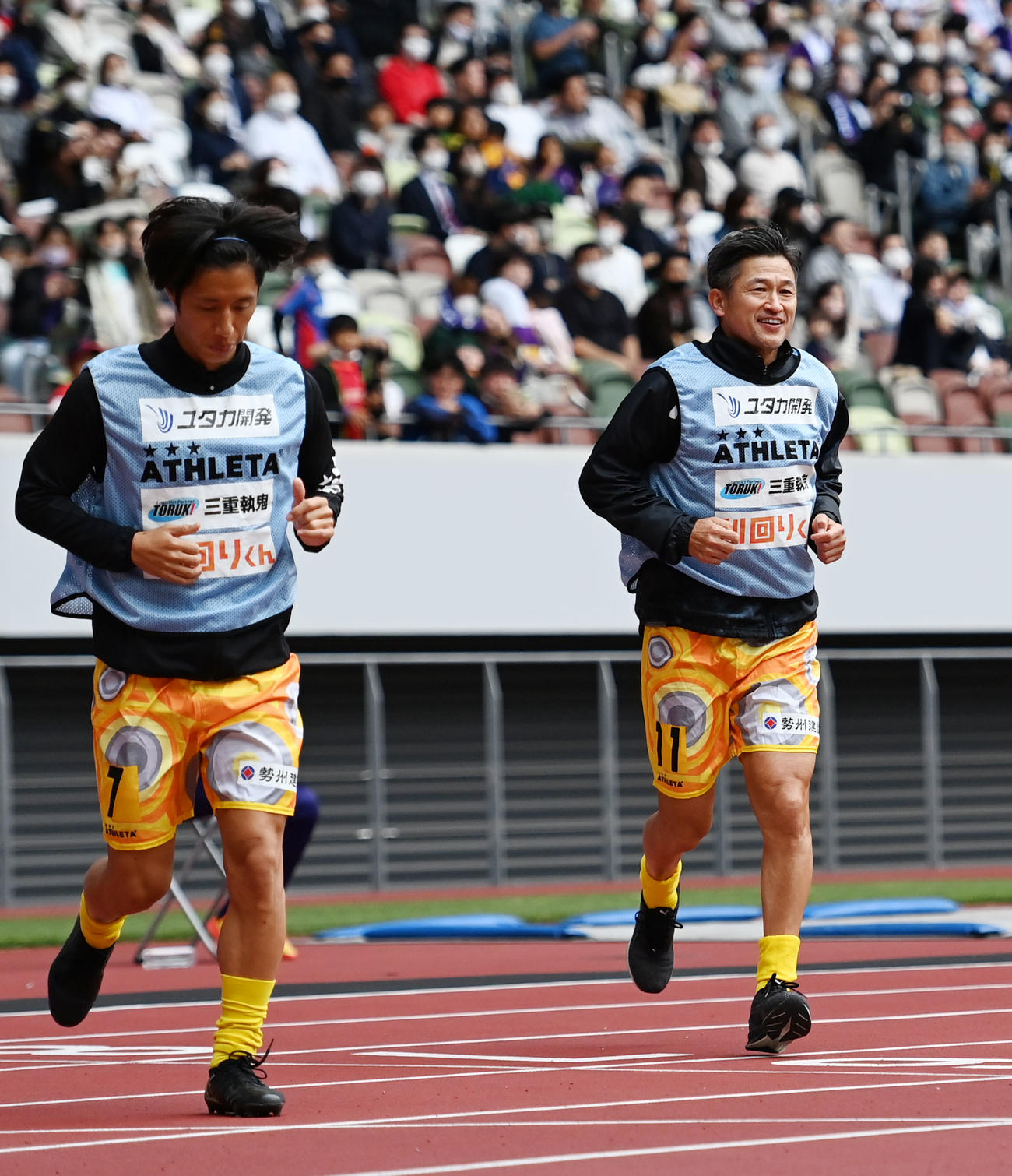 新宿対鈴鹿　後半、鈴鹿・松木のゴールで先制し笑顔で駆け寄るカズ（右）（撮影・横山健太）