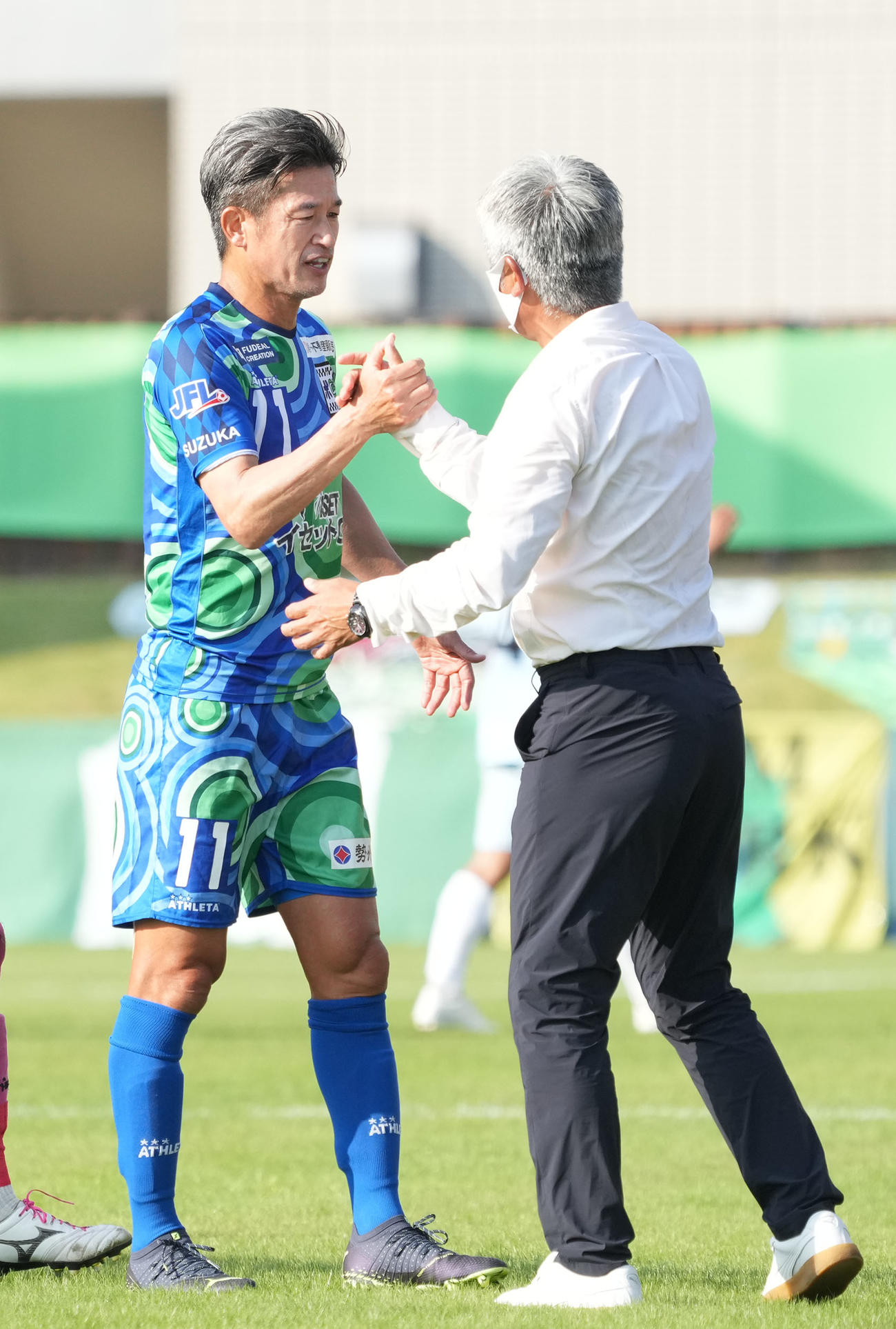 鈴鹿対滋賀　試合終了、三浦泰監督と握手を交わす鈴鹿三浦知（左）（撮影・森本幸一）