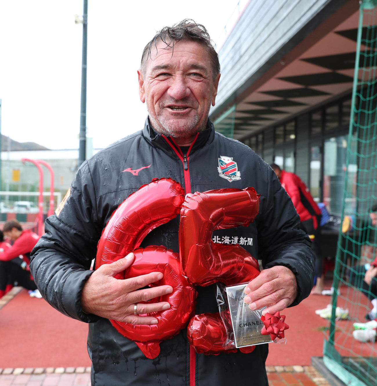 報道陣から誕生日プレゼントを手渡され笑顔を見せる札幌ペトロビッチ監督（撮影・佐藤翔太）