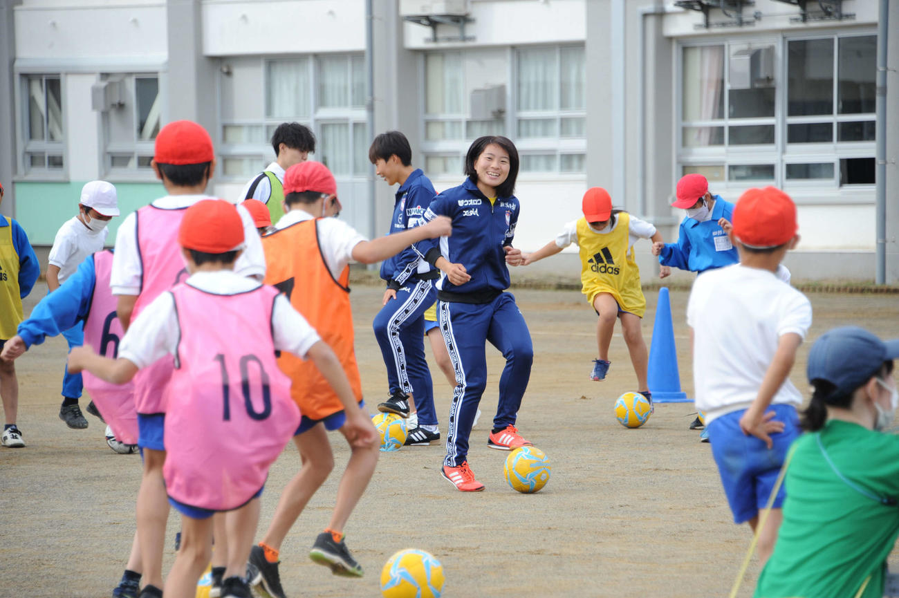 四郎丸小の5年生とともにボールを扱う新潟の武田(中央)とイ