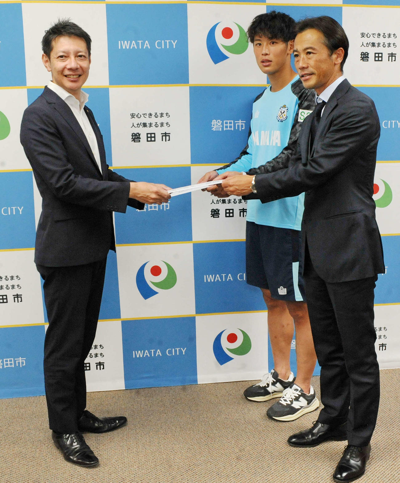 草地・磐田市長（左）に支援金の目録を手渡すJ1磐田・藤田スポーツダイレクター（右手前）とDF森岡　　