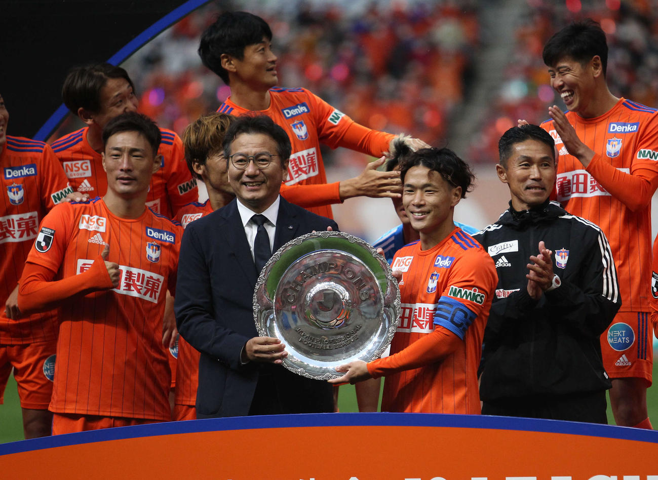 野々村チェアマン（左から2人目）から優勝のシャーレを手渡される堀米主将。右は松橋監督