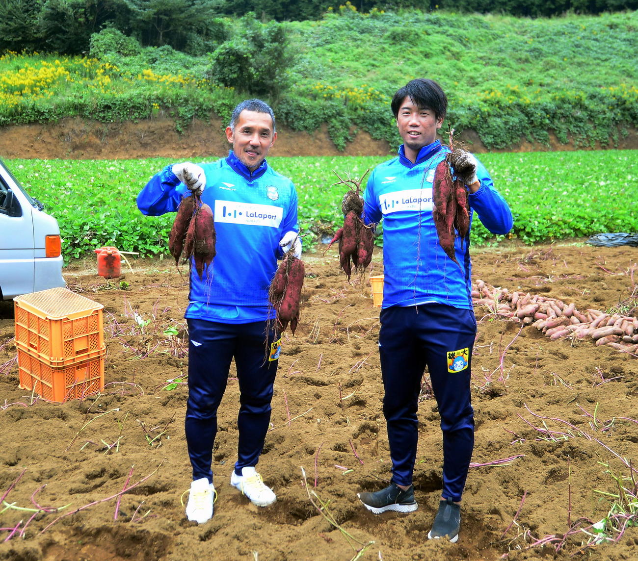 収穫したサツマイモを手に笑顔を見せる沼津伊東（左）と大迫